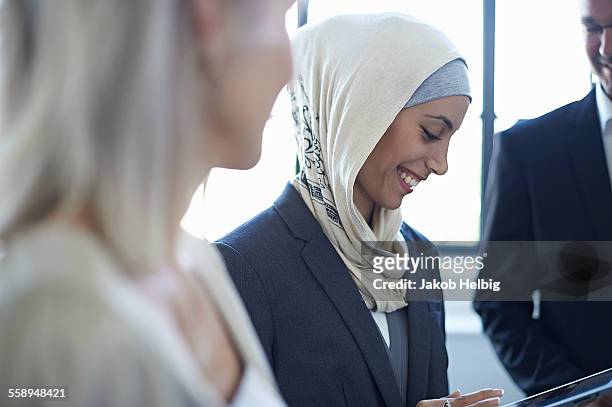 over shoulder view of businesswomen and man chatting in office - young muslim man stockfoto's en -beelden
