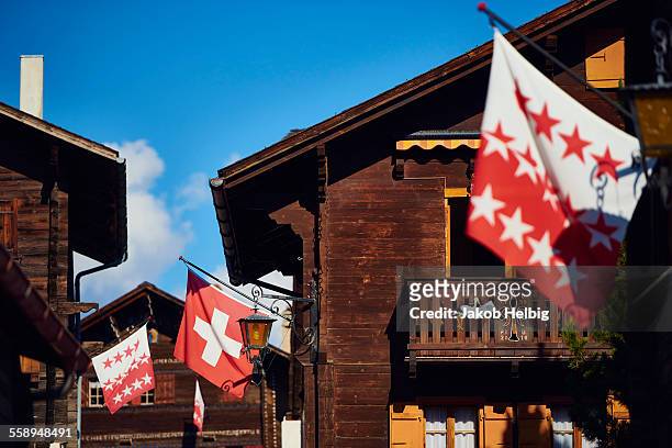 flags on chalet buildings, valais, switzerland - valais canton ストックフォトと画像