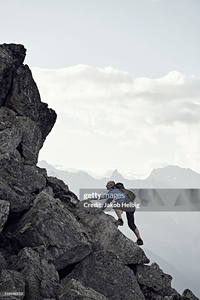 Mature man climbing up rocks, Valais, Switzerland