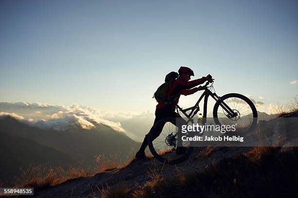 mountain biker pushing bike uphill, valais, switzerland - uphill stock-fotos und bilder