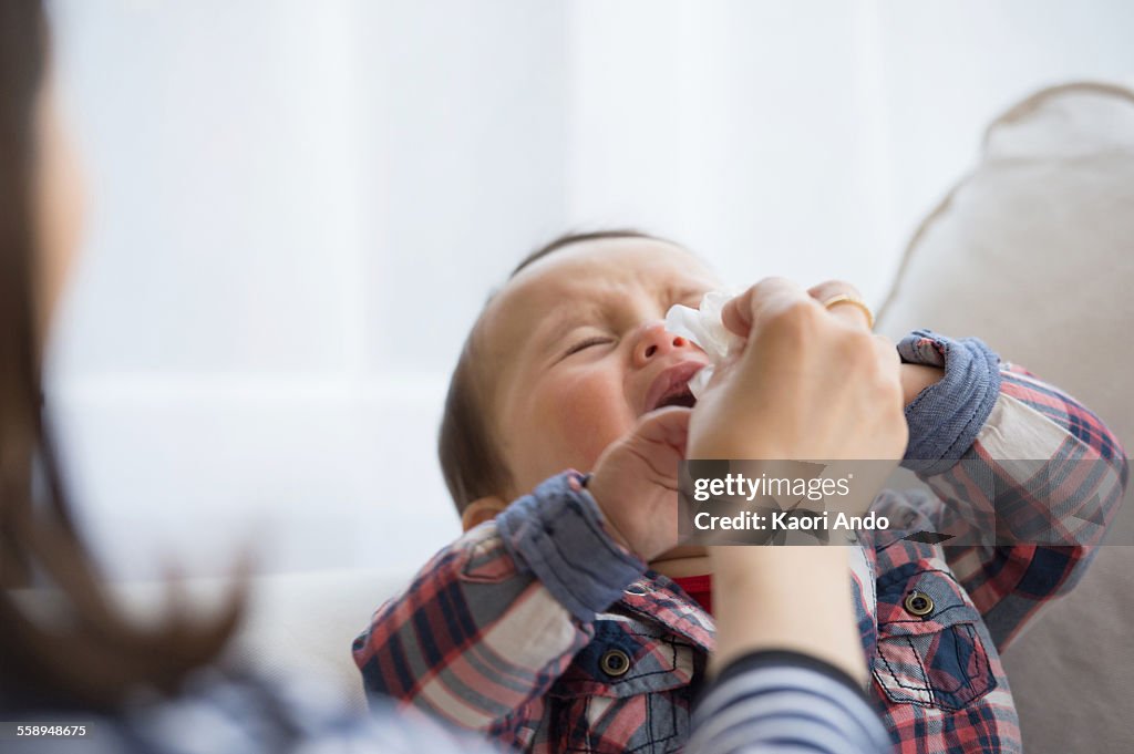 Mother wiping baby boys face