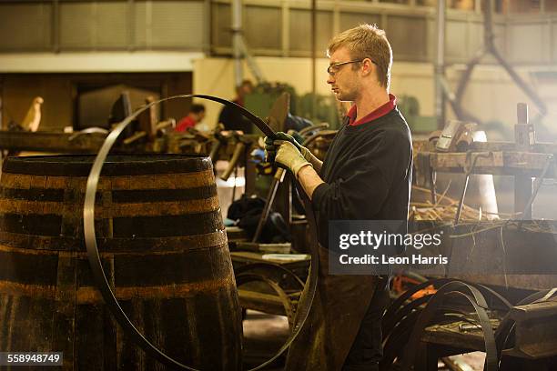 male cooper making whisky casks in cooperage - barrel stock-fotos und bilder