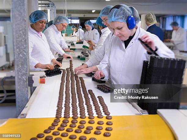 workers on production line packing chocolates in chocolate factory - fábrica de chocolate fotografías e imágenes de stock