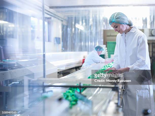 worker inspecting chocolate on production line in chocolate factory - candy factory stockfoto's en -beelden