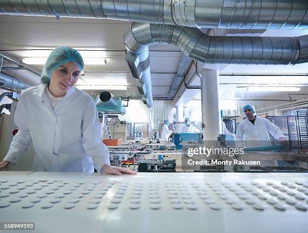 worker inspecting chocolates on production line in chocolate factory - chocolate factory stockfoto's en -beelden