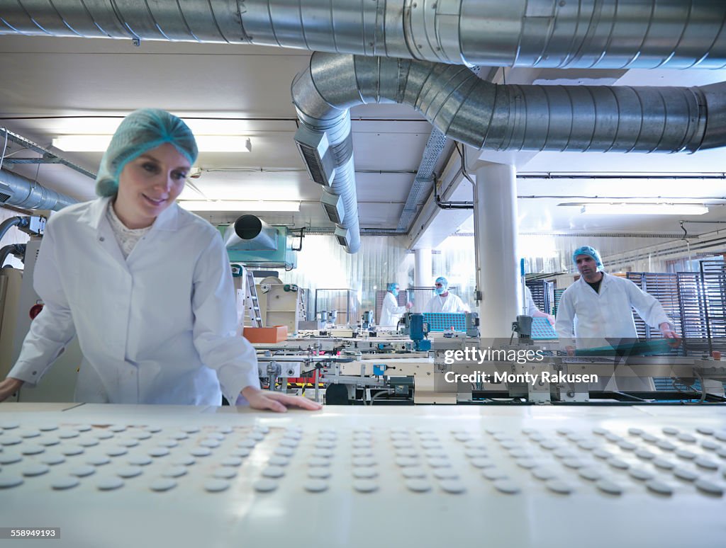 Worker inspecting chocolates on production line in chocolate factory