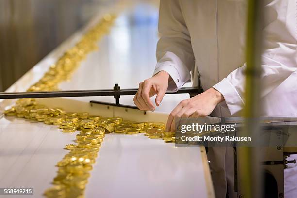 worker wrapping chocolates on production line in chocolate factory - fábrica-de-chocolate fotografías e imágenes de stock