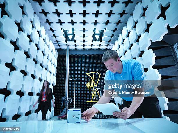 engineers checking equipment under test (eut), a continuous noise source in fully anechoic chamber with energy absorbers and bilog antenna - anechoic chamber stock pictures, royalty-free photos & images