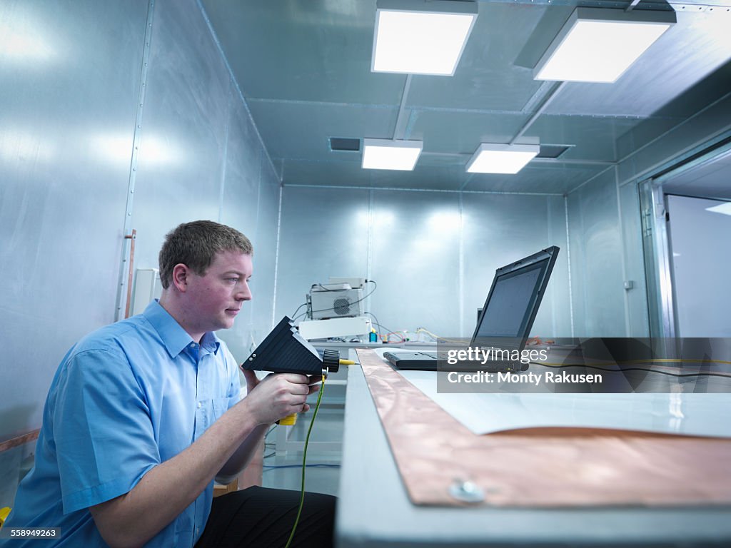 Engineer carrying out electro static discharge (ESD) testing using air discharge probe on copper table in screened room
