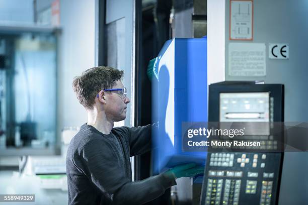 worker removing plastic part from injection moulding machine in plastics factory - injection molding stock pictures, royalty-free photos & images