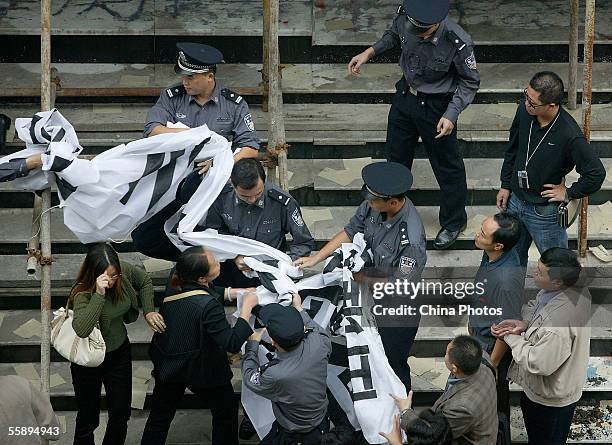 Apartment owners clash with policemen as police tear off their banners protesting about the real estate developer at the Zhihuashi Office and...