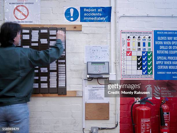 worker using time clock in factory - primo turno foto e immagini stock