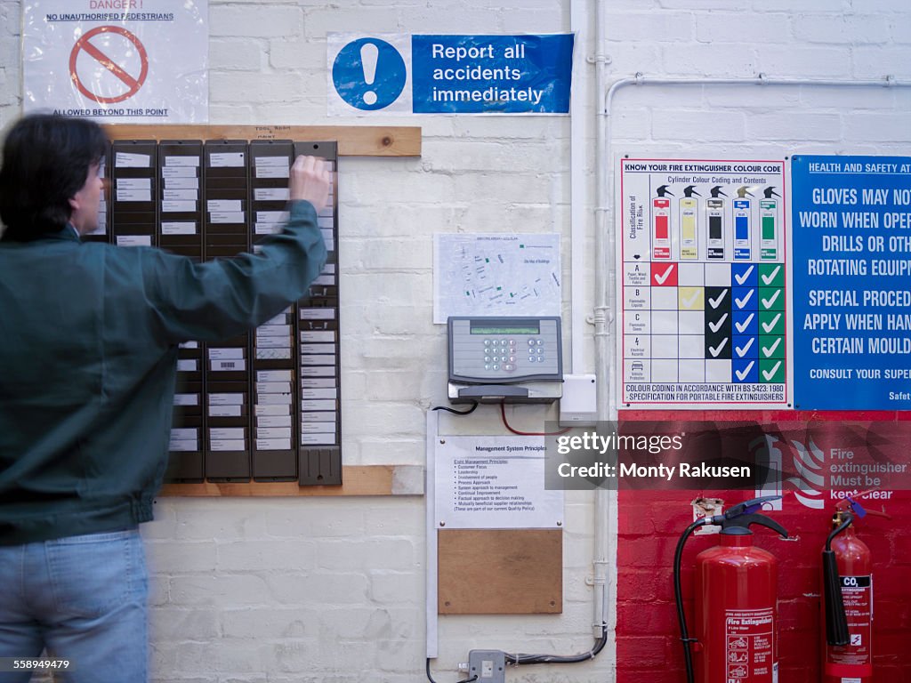 Worker using time clock in factory