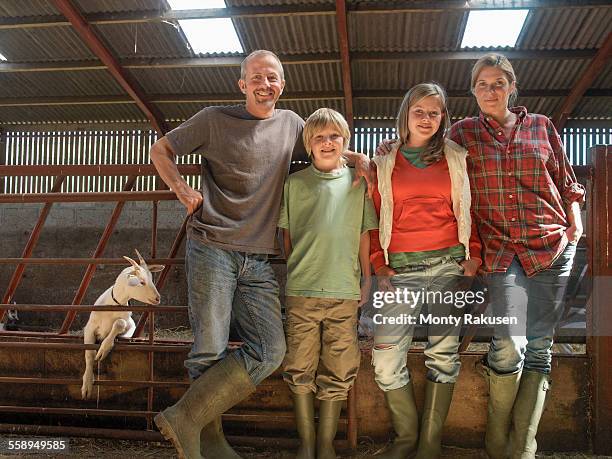 portrait of farming family in barn with goats - agriculteur local photos et images de collection