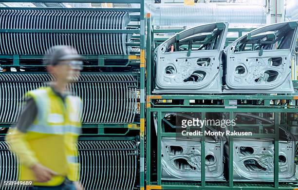 Worker passing car door parts in car factory