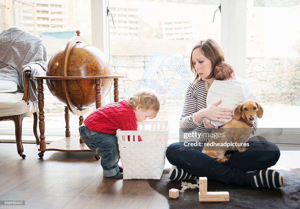 Boy playing at home with mother and baby sister