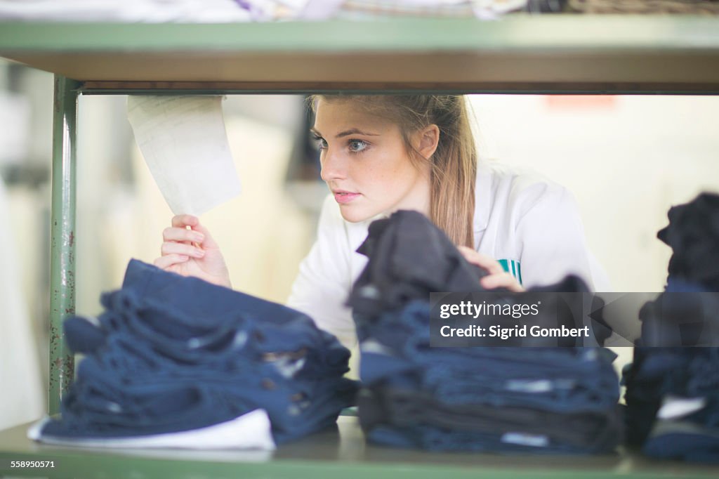 Woman behind shelves of jeans in laundry