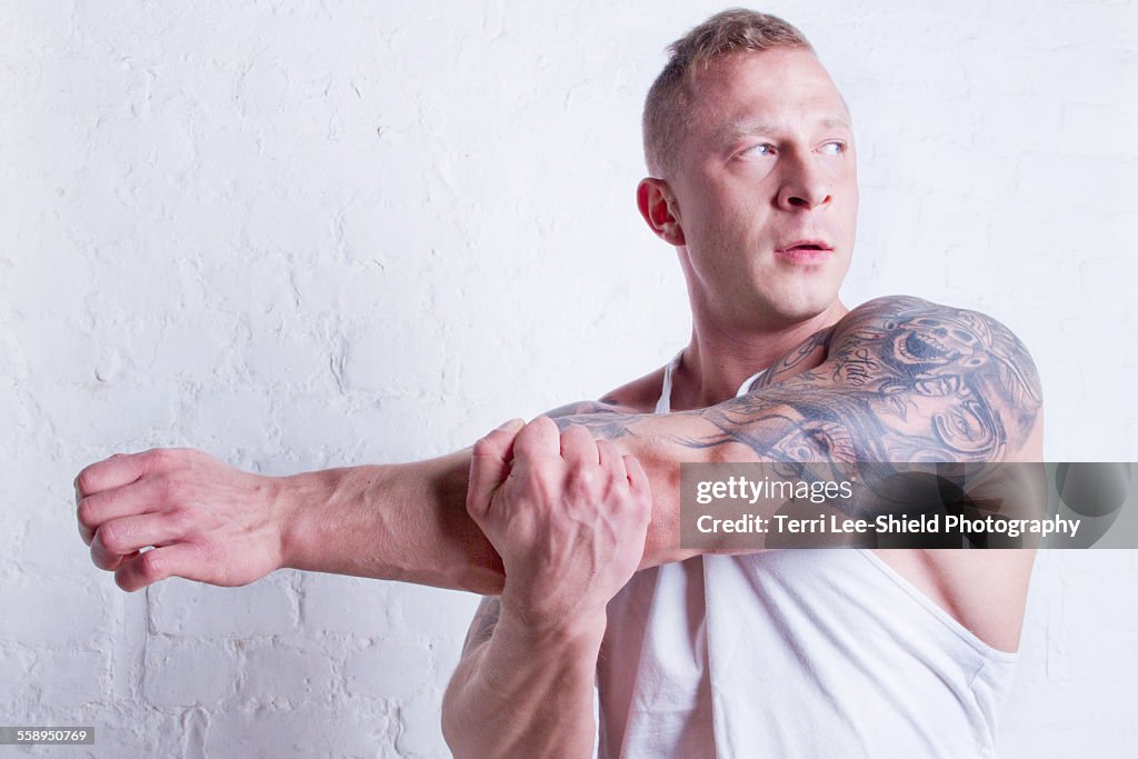 Young man with tattoos stretching arm