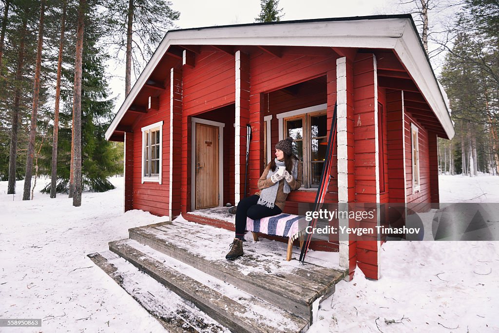 Portrait of young female skier drinking coffee on cabin porch, Posio, Lapland, Finland