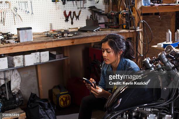 Female mechanic using mobile phone in workshop