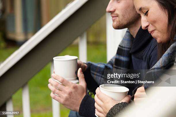 cropped shot of young couple sitting on porch step drinking coffee - seattle coffee stock pictures, royalty-free photos & images