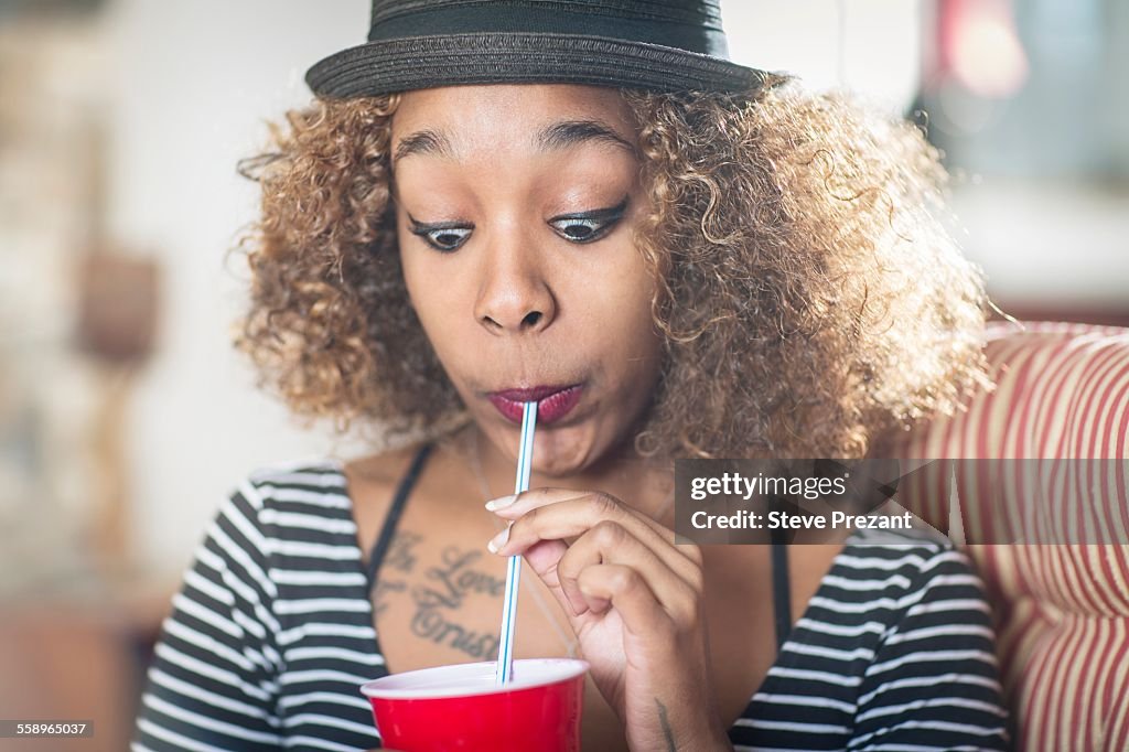 Portrait of young woman pulling a face whilst drinking soft drink