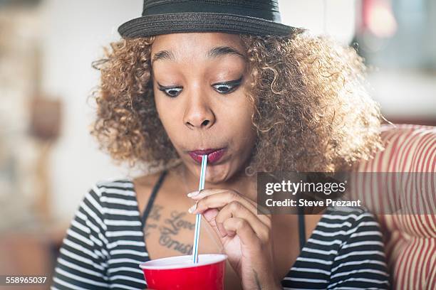 portrait of young woman pulling a face whilst drinking soft drink - sugrör bildbanksfoton och bilder