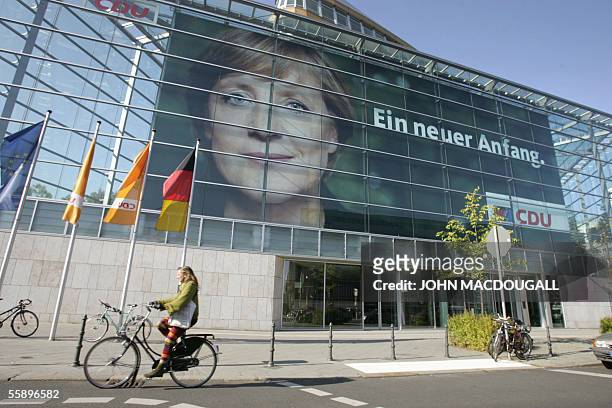 Woman cycles past a poster featuring Christian Democratic Union leader Angela Merkel at the CDU headquarters in Berlin 11 October 2005. Merkel is set...
