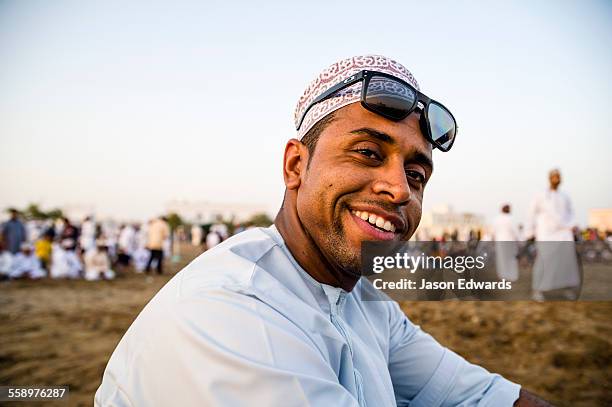 a muslim man wearing a traditional kuma and sunglasses at a bullfight. - 阿曼 個照片及圖片檔