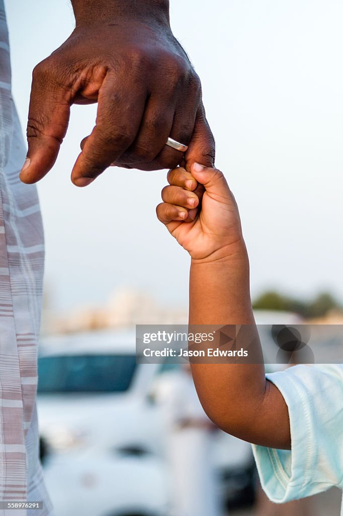 A father holds his daughters hand on the way to a traditional bull fight.