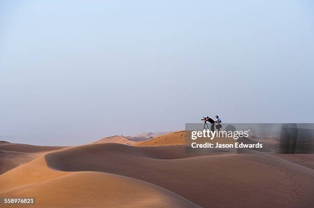 a television crew films the sunset from a sand dune in the desert. - camera man stock pictures, royalty-free photos & images