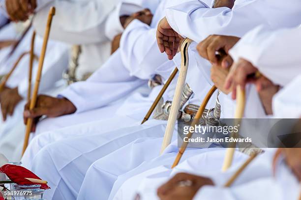 muslim elders holding ceremonial canes while they watch camel racing in the desert. - people from oman stockfoto's en -beelden