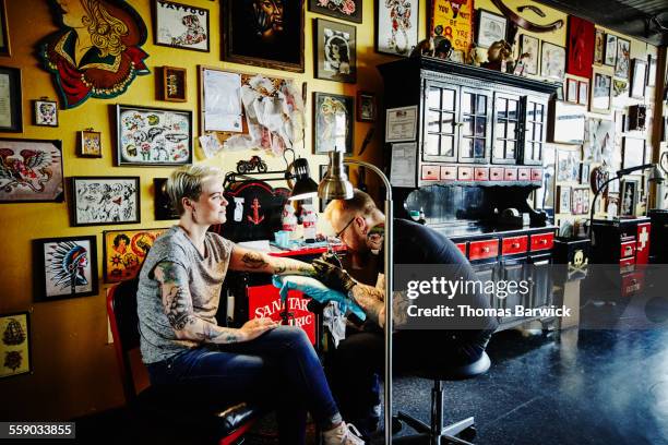 tattoo artist tattooing arm of female customer - tattooing stock-fotos und bilder