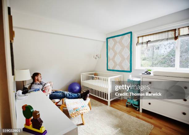 father falling asleep while rocking baby to sleep - cot imagens e fotografias de stock