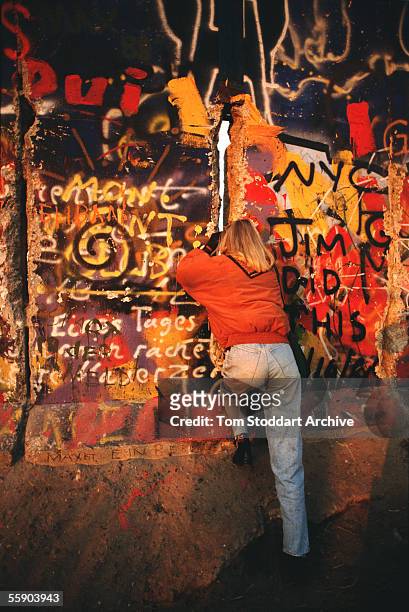 Girl peers through a gap in the Berlin Wall on the morning of November 10th 1989, the day the wall finally came down.