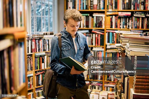 Young man reading in second hand bookstore