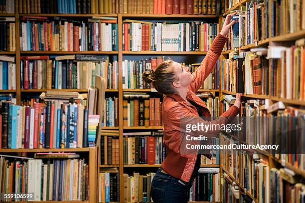 Young woman reading in second hand bookstore