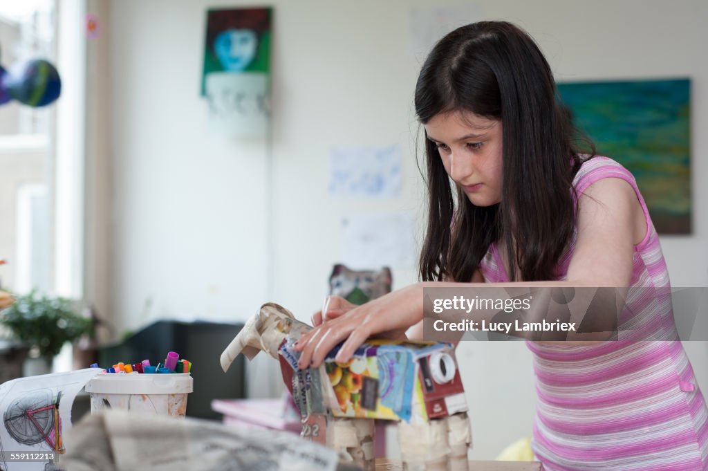 Girl crafting a horse from paper mache and waste