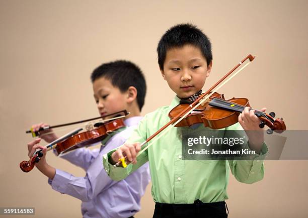 two young boys play violin - musikalische begleitung stock-fotos und bilder