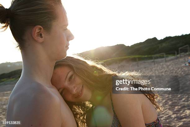 teenage girl and boy on beach with sun flare - erstereignis stock-fotos und bilder