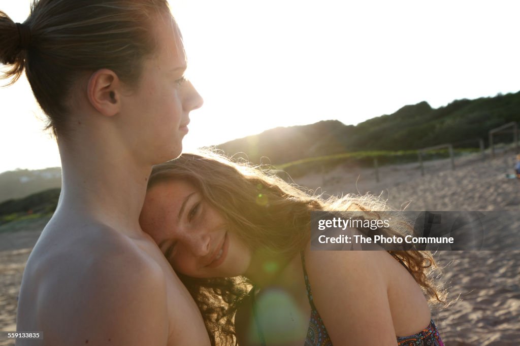 Teenage girl and boy on beach with sun flare