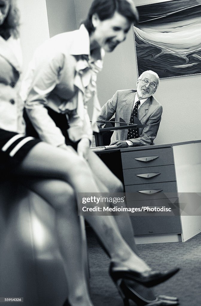 Businessman eavesdropping on two businesswomen