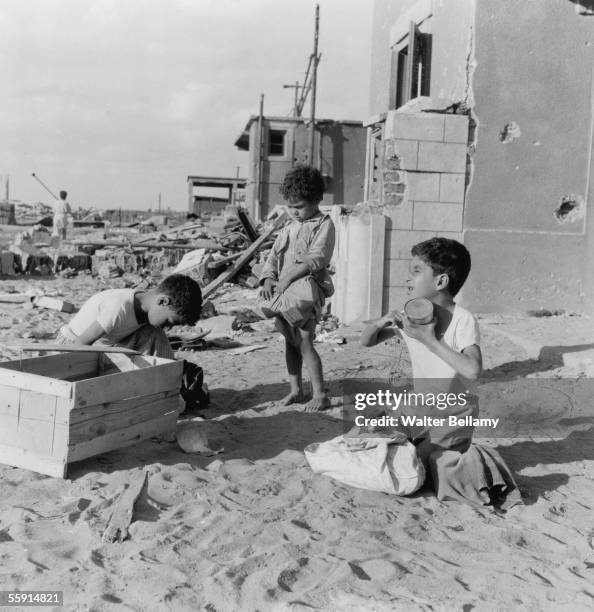 Local children scavenge for food amongst the ruins of their city during the Suez Crisis, 15th November 1956.