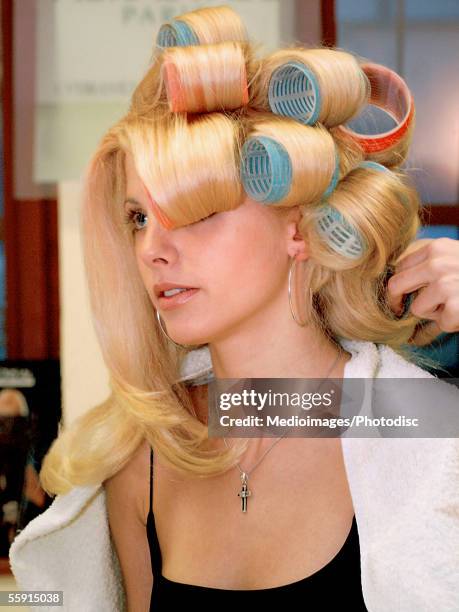 hairdresser putting curlers in a mid adult woman's hair - hair curlers stockfoto's en -beelden