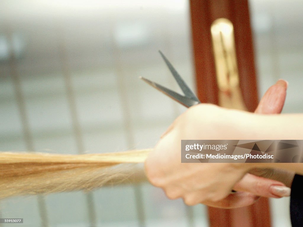 Close-up of a hairdresser's hand cutting a woman's hair with scissors