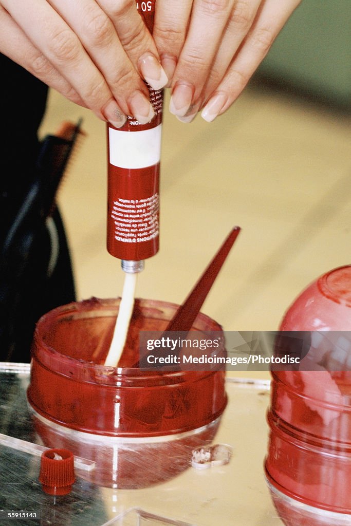 Close-up of a woman's hand squeezing hair dye from a tube