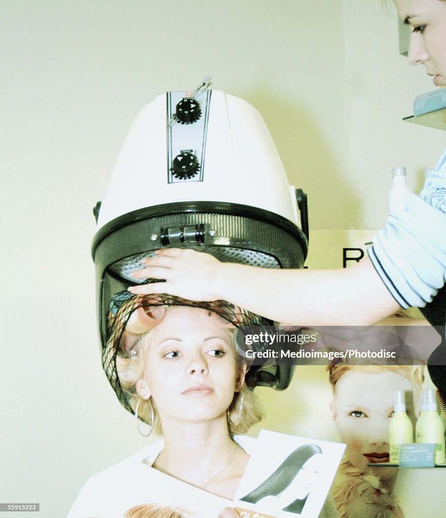 Mid adult woman with hair in rollers under dryer