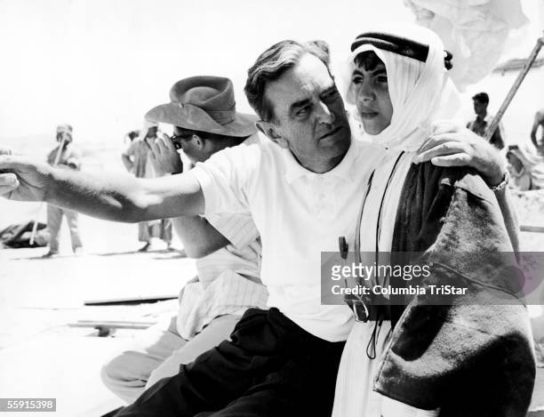 British film director David Lean explains a scene to a young actor in Arab dress on the set of his film 'Lawrence of Arabia,' 1962.