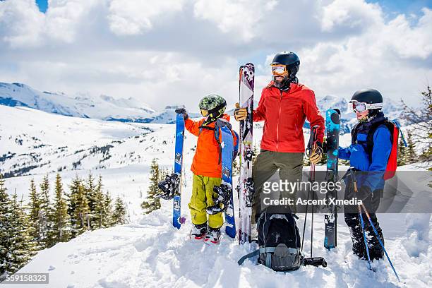 father and sons relax in fresh snow, with skiis - sport d'hiver photos et images de collection