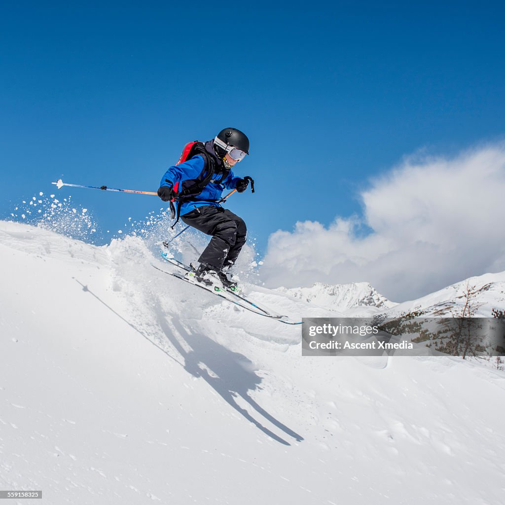 Young skier in mid air jump through fresh snow, mt